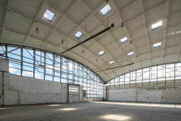 Corner of huge empty industrial warehouse. Modern building. Hemispherical reinforced concrete load bearing roof. Metal construction. Unique architecture.