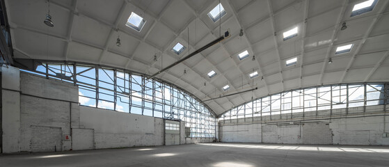 Corner of huge empty industrial warehouse. White interior. Hemispherical reinforced concrete load bearing roof. Metal construction. Unique architecture.