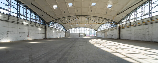 Huge empty industrial warehouse. White interior. Unique architecture. Hemispherical reinforced concrete load bearing roof with windows. Modern building.