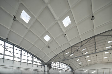 Hemispherical reinforced concrete load bearing roof with windows in huge industrial warehouse. White interior. Unique soviet architecture.