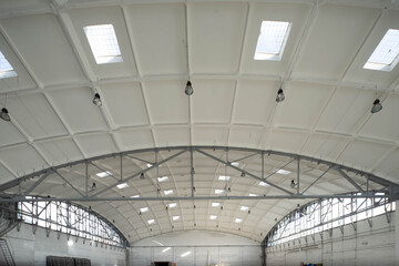 Hemispherical reinforced concrete load bearing roof with windows in huge industrial warehouse. White interior. Unique soviet architecture.
