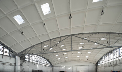 Hemispherical reinforced concrete load bearing roof with windows in huge industrial warehouse. White interior. Unique soviet architecture.