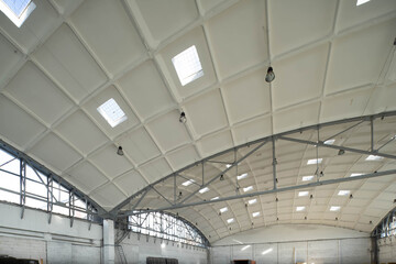 Hemispherical reinforced concrete load bearing roof with windows in huge industrial warehouse. White interior. Unique soviet architecture.