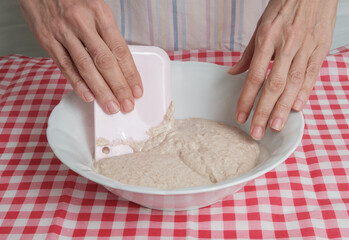 Kneading a dough of bread in a bowl. Female hands working. Making pizza. Cooking at home. Homemade food. Italian cloth.