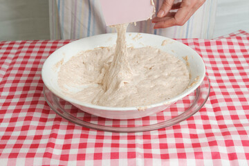 Kneading a dough of bread in a bowl. Female hands working. Making pizza. Cooking at home. Homemade food. Italian cloth.