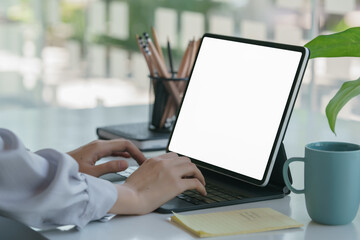 Side view of businesswoman working on digital tablet, mug and schedule book on counter bar.