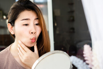 Asian woman doing face yoga , exercises for anti-aging, slimming face in front of mirror