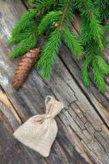 Small bag of burlap and branch green spruce with cone background of a wooden old table