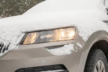 Car headlight on after automatic engine start. Car in the snow after a heavy snowfall. © сергей назаров