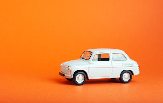 White car on colored background. Model white retro toy car on orange background. Miniature car with copyspace