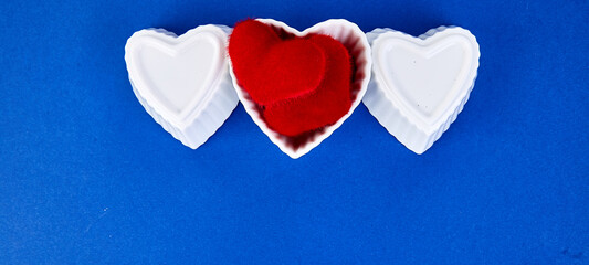 Banner of White ceramic hearts with red plush hearts on blue background.