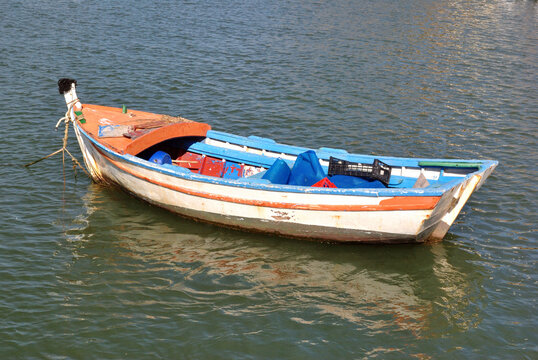Colourful Empty Rowing Boat Anchored in Rippled Waters 
