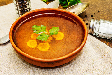 Transparent chicken broth with carrot, parsley and spices