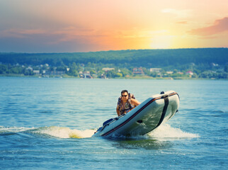 Man drives an inflatable motor boat in lake or sea