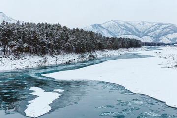 Winter landscape with rocks, stones and ice in the river. The trees and stones are covered with snow