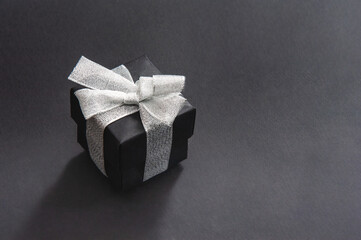 A black gift box tied with a silver ribbon with a bow. Close up. Isolated