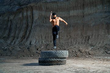 Handsome strong man jumping on wheel during evening workout