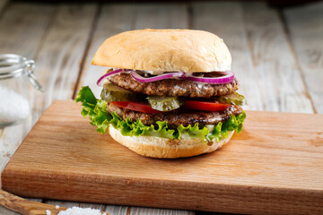 Closeup on double patty burger with pickles on the wooden board