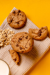 Oatmeal chocolate chip cookies on a kitchen towel on a yellow background with space for text
