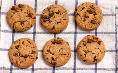 Oatmeal chocolate chip cookies on a checkered towel on a pastel pink background with space for text