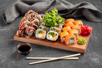Side view on sushi roll assorted set on the wooden board with soy sauce
