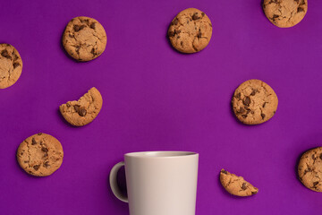 Top view of a purple background with chocolate chip cookies and a mug. the concept of the coffee break, entertainment