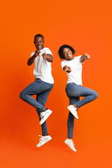 Fototapeta na wymiar Emotional black couple posing on orange studio background