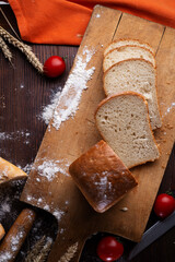 assortiment of tasty fresh  bread. served at  wooden table with cherry tomatos and wheat ears.
