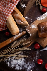 assortiment of tasty fresh  bread. served at  wooden table with cherry tomatos and wheat ears.