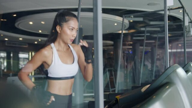 Young athlete Asia lady in sportswear exercise run on treadmill fat burning workout in fitness class. Doing cardio training, self-isolation, social distancing, quarantine for corona virus prevention.