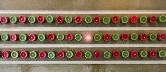 Overhead view of red and green candles lined up, one lit.