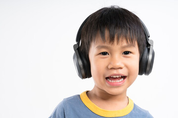 Cute smiling Asian boy about 4 years old wearing headphone and listening to music