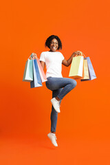 Joyful black lady with shopping bags jumping up