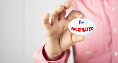 Vaccination campaign button pin in caucasian male fingers. Copy-space added