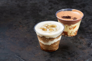 Banoffee pie dessert in cup with fresh banana on wooden background, selective focus, copy space