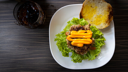Hamburger with cheese and fried potatoes,green salad on a wooden table