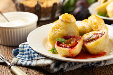 Dumplings with plums, topped with plum sauce or served with cream and sugar.