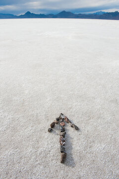 Pebbles arranged on salt flat in the shape of an arrow.