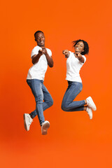 Happy black lovers posing on orange studio background