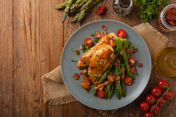 Roasted chicken breast, served on asparagus with tomato sauce, dried tomatoes. Top view.