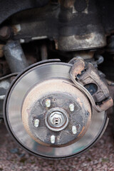Old steel ventilated brake disk with used brake pads are ready for removing, rear wheel