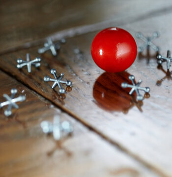 Ball and jacks counters on a wooden surface.