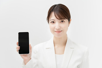 スマートフォンを持つ、白いスーツ姿の女性