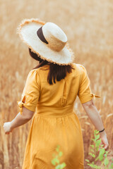 woman in yellow sundress walking by wheat field