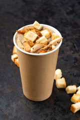 French cuisine hot food delivery - Close-up of mushroom soup with chicken meat in disposable paper cups on a dark stone surface. Healthy food concept