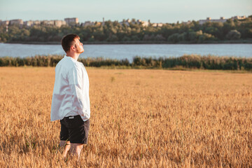 Naklejka na ściany i meble man walking on sunset in wheat field