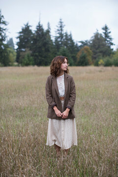 Portrait of seventeen year old girl wearing tweed  blazer, standing in field of tall grasses, Discovery Park, Seattle, Washington