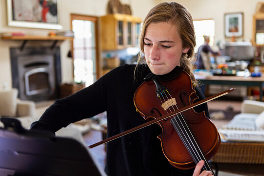 Teenage girl practicing violin at home