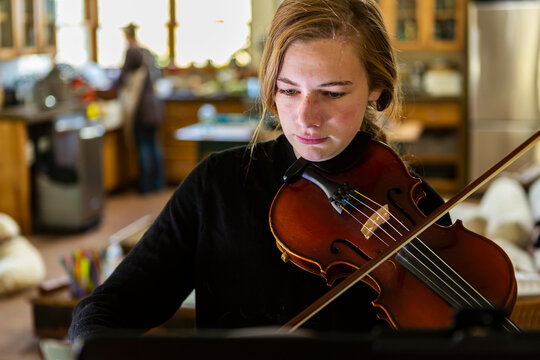Teenage girl practicing violin at home