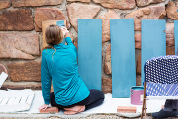 Teenage girl painting wooden shelves blue.